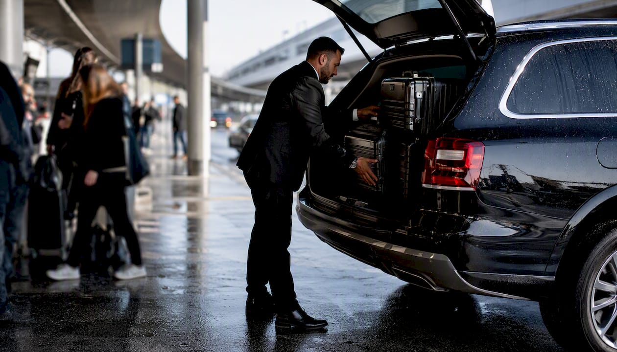 Chauffeur loading luggage at airport curbside